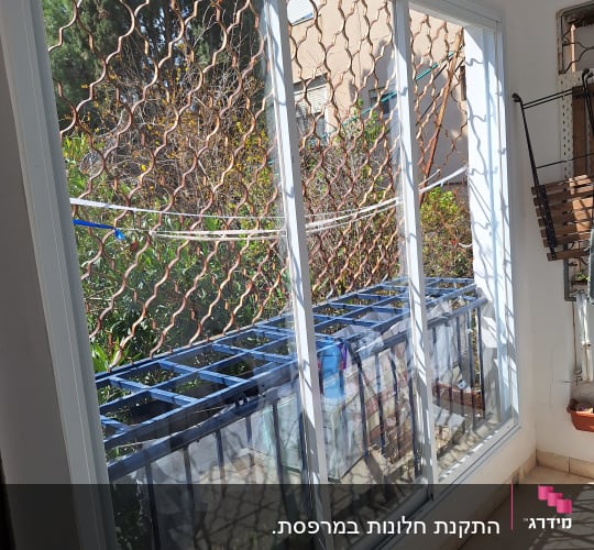 חלון אלומיניום עם מסגרת לבנה ומעקה חיצוני
